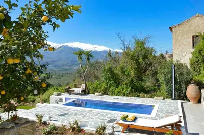 a swimming pool in a garden with mountains in the background at Villa Iro - Private Pool & Tranquility in Káïna