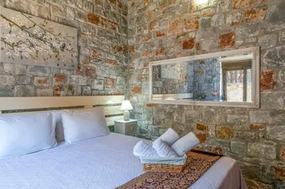 a bedroom with a stone wall with a bed and a mirror at Villa Kamaraki in Patellárion