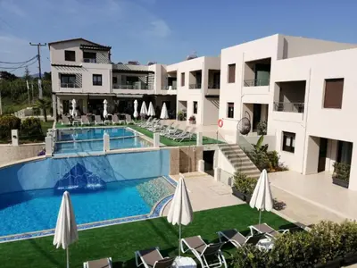 a hotel with a swimming pool and lawn with chairs and umbrellas at Carisa Suites and Apartments in Maleme