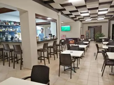 a restaurant with tables and chairs and a man standing at a counter at Carisa Suites and Apartments in Maleme