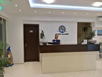 a woman standing at a counter in a lobby at Carisa Suites and Apartments in Maleme