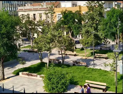 two people walking in a park with benches and trees at GreenView Chania Center Luxury Suite in Chania Town