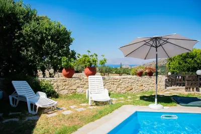 two chairs and an umbrella next to a pool at Villa Antonia in Gramvousá