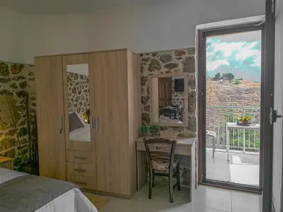 a bedroom with a bed and a desk and a window at Achlades The Mountain Paradise Villas - Suite with pool and balcony with amazing view! in Aletrouvárion