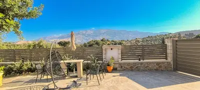 a patio with chairs and a table and a fence at Achlades The Mountain Paradise Villas - Suite with pool and balcony with amazing view! in Aletrouvárion