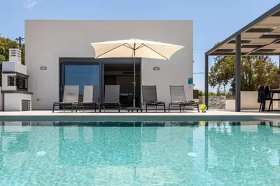 a swimming pool with an umbrella and chairs at Menta Villa by Vintage Travel in Tavronitis