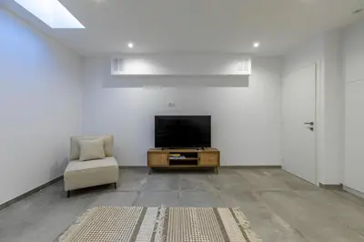 a living room with a television and a chair at Myrtle Villa by Vintage Travel in Tavronitis