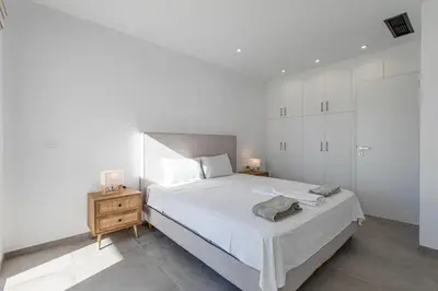 a white bedroom with a large bed and a night stand at Myrtle Villa by Vintage Travel in Tavronitis
