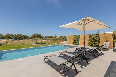 a patio with chairs and an umbrella next to a swimming pool at Myrtle Villa by Vintage Travel in Tavronitis