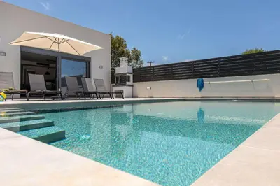 a swimming pool with an umbrella and some chairs at Sage Villa by Vintage Travel in Tavronitis
