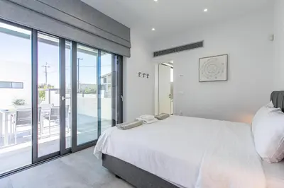 a bedroom with a white bed and a large window at Sage Villa by Vintage Travel in Tavronitis