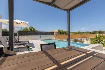 a patio with a table and a swimming pool at Sage Villa by Vintage Travel in Tavronitis