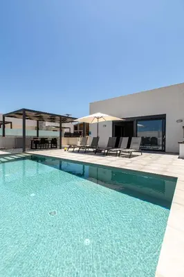 a swimming pool with chairs and a building at Sage Villa by Vintage Travel in Tavronitis