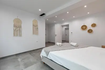 a white bedroom with a bed and two paintings on the wall at Diktamos Villa by Vintage Travel in Tavronitis