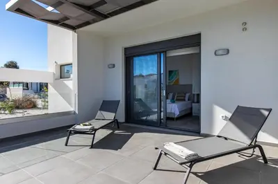 two chairs on a patio with a view of a bedroom at Diktamos Villa by Vintage Travel in Tavronitis