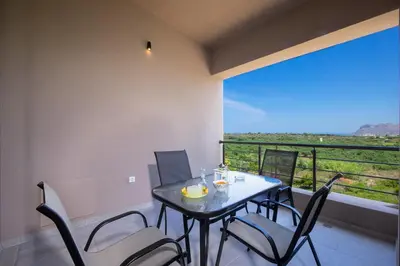 a dining room with a table and chairs and a balcony at Didas Serenity Breeze in Kounoupidhianá