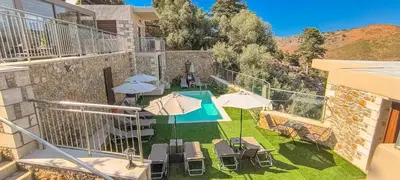a balcony with umbrellas and chairs and a swimming pool at Achlades The Mountain Paradise Villas - Suite with a Private Jacuzzi, Pool, and a Balcony with an Amazing View! in Aletrouvárion