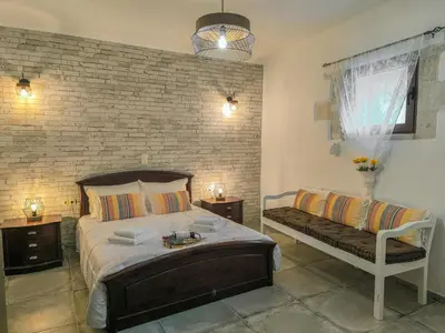 a bedroom with a large bed and a bench at Achlades The Mountain Paradise Villas - Suite with a Private Jacuzzi, Pool, and a Balcony with an Amazing View! in Aletrouvárion