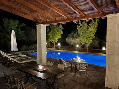 a patio with a table and a pool at night at Villa Domenico in Vryses