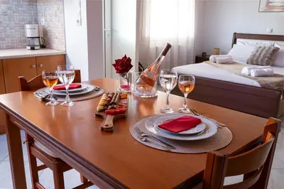 a wooden table with two plates of food and wine glasses at Haris home in Daratso