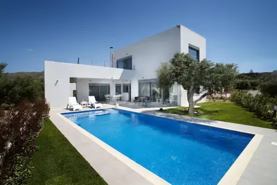 a villa with a swimming pool in front of a house at Gramvousa Villas in Kissamos