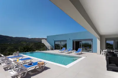 a swimming pool with lounge chairs and a house at Gramvousa Villas in Kissamos