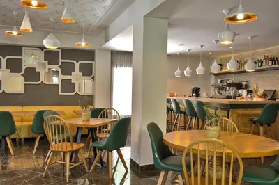 a restaurant with wooden tables and green chairs at Elia Bettolo Hotel in Chania Town