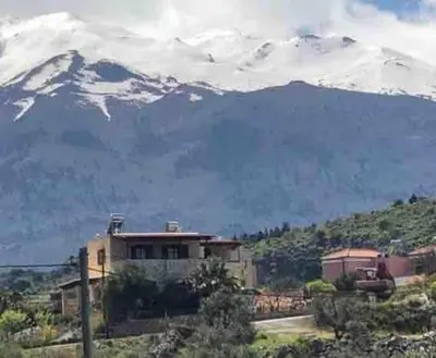 a house in front of a snow covered mountain at Villa Aris in Crete with private pool en private parking! in Neo Chorio