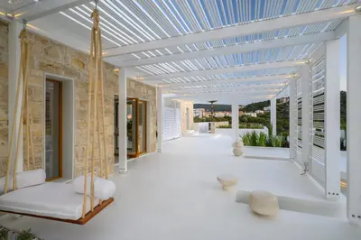a patio with white furniture and a blue ceiling at Studios Stylianos in Kounoupítsa