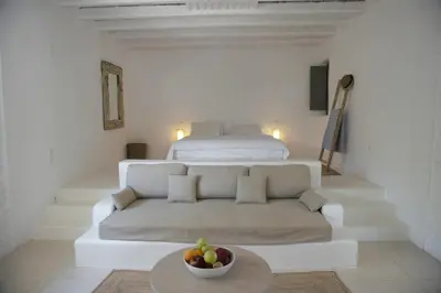 a white living room with a couch and a bed at Studios Stylianos in Kounoupítsa
