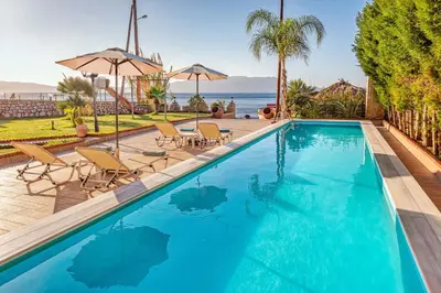 a swimming pool with chairs and a view of the ocean at Julia's Cosy Apt in Ravdhoúkha