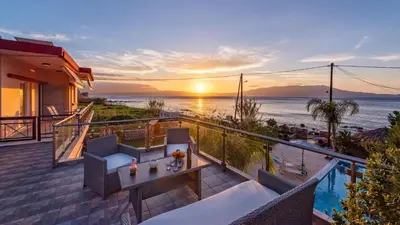 a balcony with a view of the ocean at sunset at Julia's Cosy Apt in Ravdhoúkha