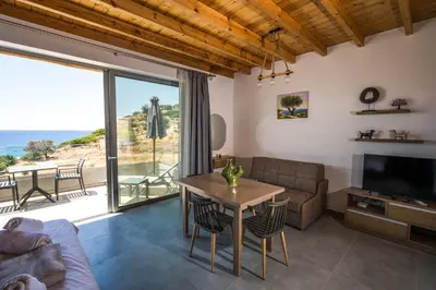 a living room with a table and a view of the ocean at Michalis-Nina studios in Livanianá