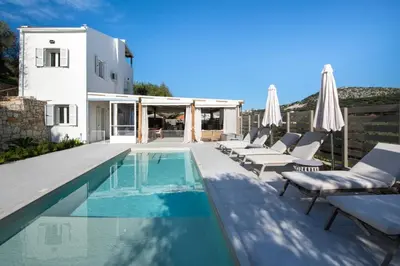 a swimming pool with lounge chairs and a house at Villa Mareli - Beachside Villa with Heated Pool in Almirida