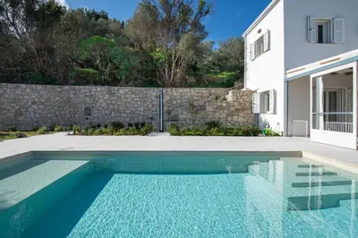 a swimming pool in front of a white house at Villa Mareli - Beachside Villa with Heated Pool in Almirida