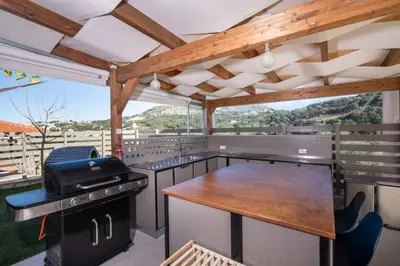 an outdoor kitchen with a grill and a table at Villa Mareli - Beachside Villa with Heated Pool in Almirida