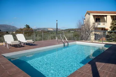 a swimming pool with two chairs sitting on a deck at Villa Pervana- Private pool - Close to the Beach in Arménoi