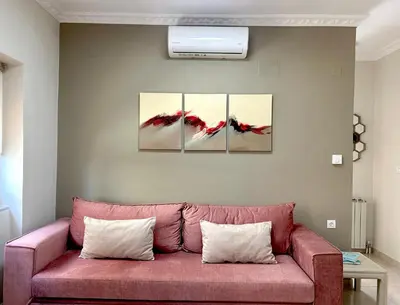 a pink couch in a living room with three paintings at Nerina Home Chania in Chania Town