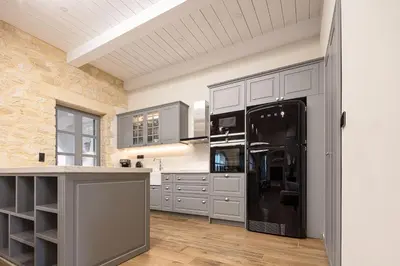 a kitchen with gray cabinets and a black refrigerator at Artemis Apollonas Villa I Luxury Escape with Pool in Káïna