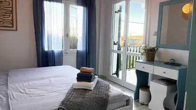 a bedroom with a bed and a window with a balcony at Kalimera Kalyves Apartment in Kalyves