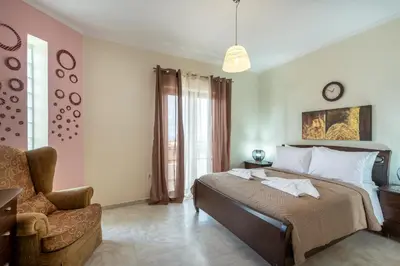 a bedroom with a bed with a chair and a clock at Sunlit sea view apartments in Stalos
