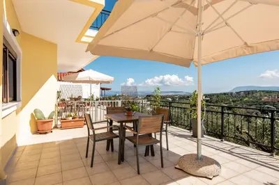 a patio with a table and chairs and an umbrella at Sunlit sea view apartments in Stalos