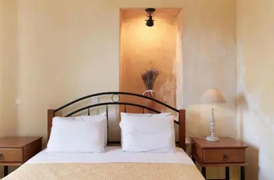 a bedroom with a bed with white pillows and a lamp at Elaiona Country Home in Xamoudhokhórion