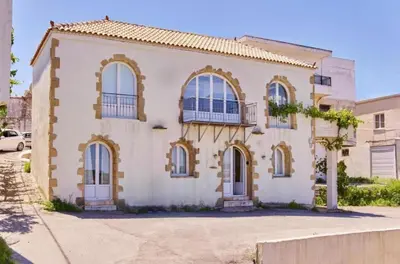 a white house with blue windows on a street at Elaiona Country Home in Xamoudhokhórion