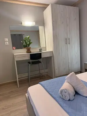 a bedroom with a bed and a desk with a chair at Dom Suites in Aghii Apostoli