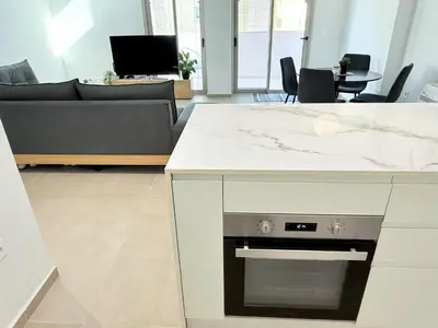a living room with a kitchen with a stove at Azure Loft - 3min walk to beach, 10min to Old Town in Chania Town