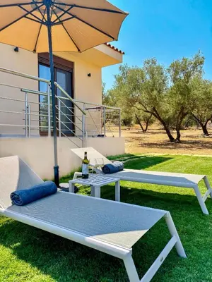 two beds and an umbrella in front of a house at Terra Blue Suites - Nefeli in Kalyves