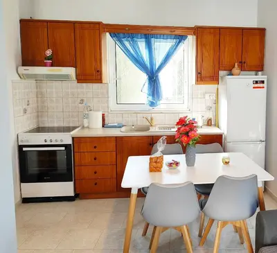 a kitchen with a white table and chairs and a window at Nature House Vlatos in Vlátos
