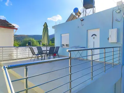a balcony with chairs and tables on a house at Nature House Vlatos in Vlátos