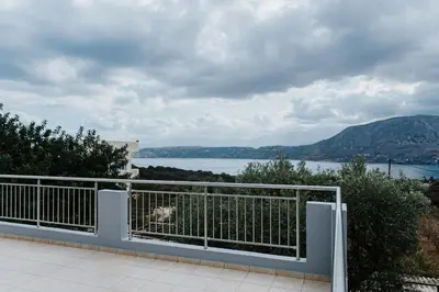 a dog sitting on a fence looking out at the water at AITHRA seaside in Arónion